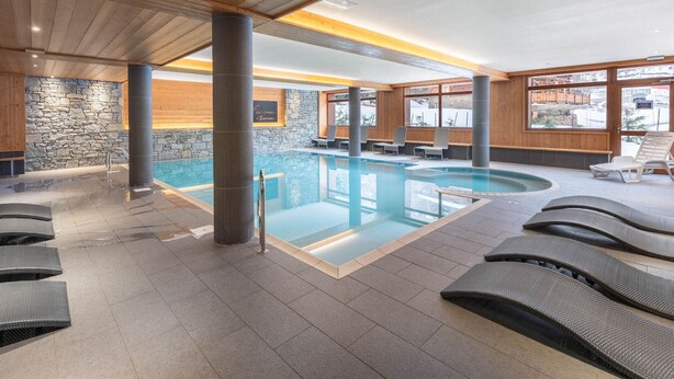 An indoor swimming pool with lounge chairs and stone walls. - Apartment with wellness area in Les Saisies (Les Saisies)