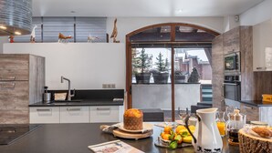 A modern kitchen with a large island, wooden cabinets, and a view of the outside. - Spacious loft with spa, pool, gym, and parking (Les Saisies)