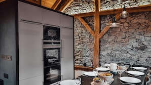 Uma cozinha moderna com parede de pedra, vigas de madeira e bancada preta.