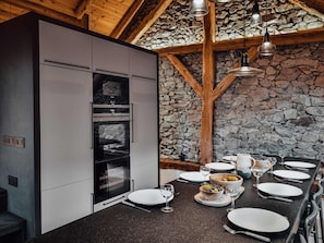 Una cucina moderna con parete in pietra, travi in legno e piano di lavoro nero.