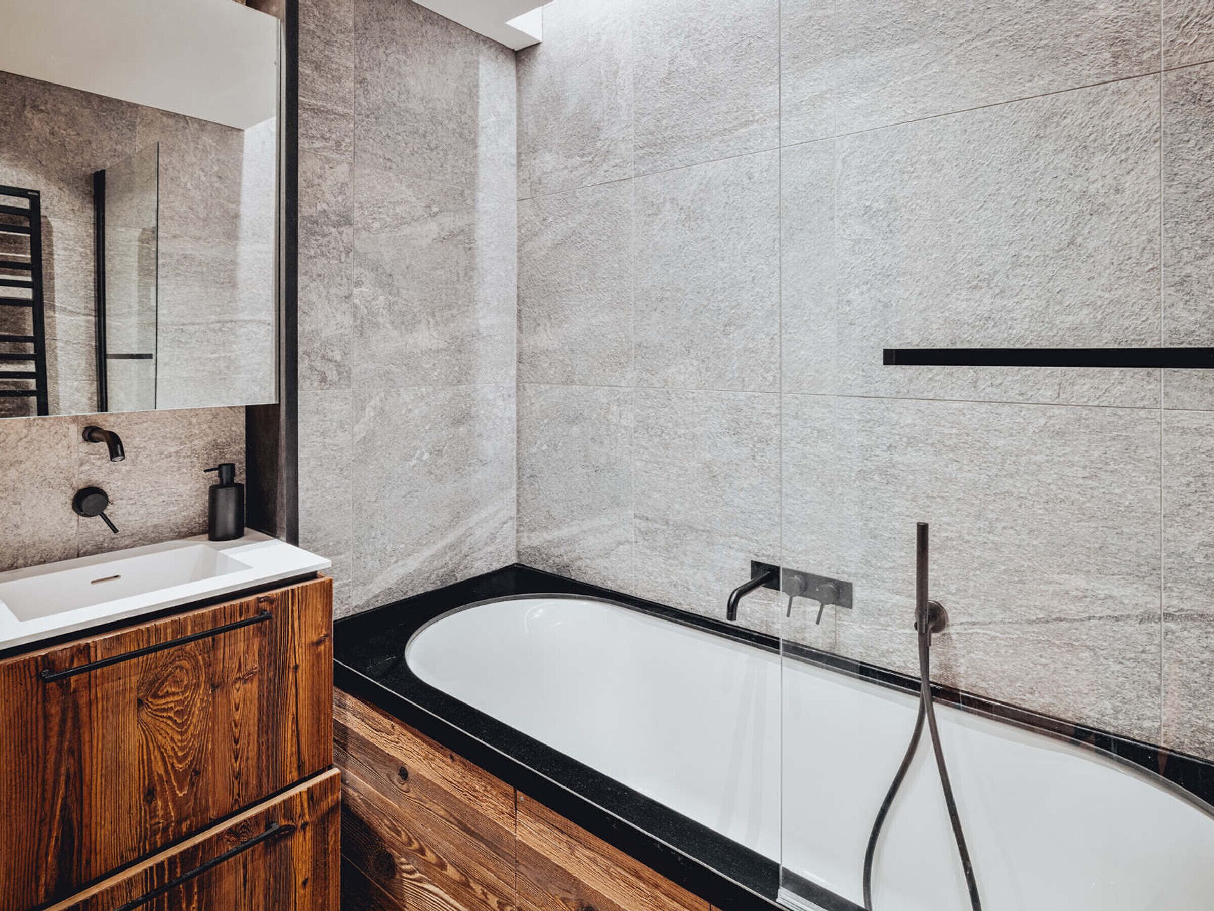A modern bathroom with a freestanding bathtub, a wooden vanity, and a large mirror.