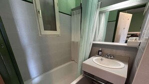 Une salle de bain avec une baignoire, un lavabo et un miroir.