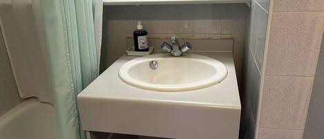 Un baño con un lavabo blanco, un espejo y un perchero para toallas.