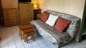 Une pièce chaleureuse avec un canapé à motifs, un meuble en bois, une télévision et une petite table en bois.