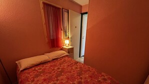 Une chambre à coucher avec une couvre-lit à motifs floraux, une lampe de chevet et une porte donnant sur un balcon.