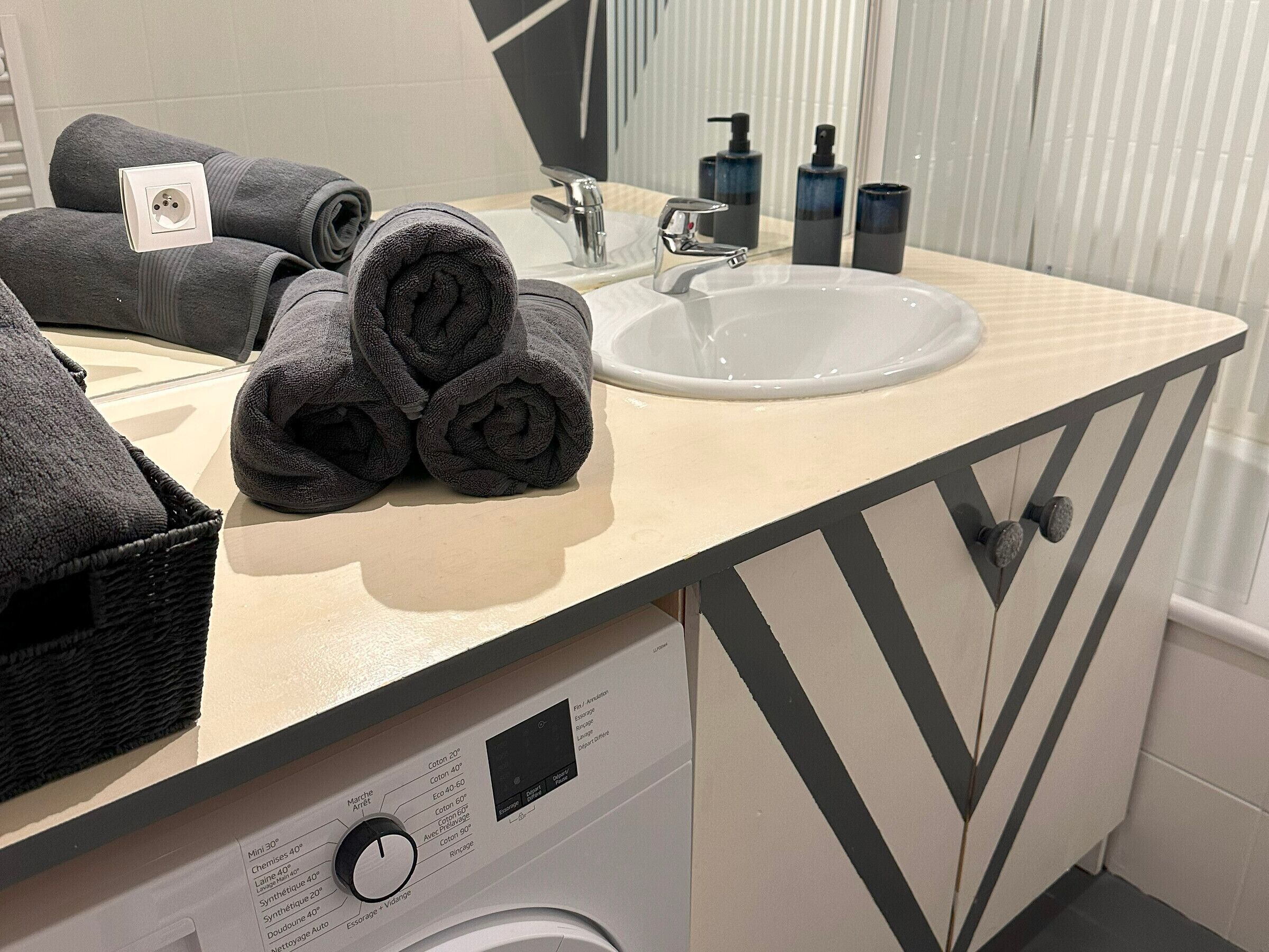 A bathroom with a sink, mirror, and a washing machine.