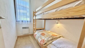 A bunk bed room with a window, a heater, and a wall-mounted light.