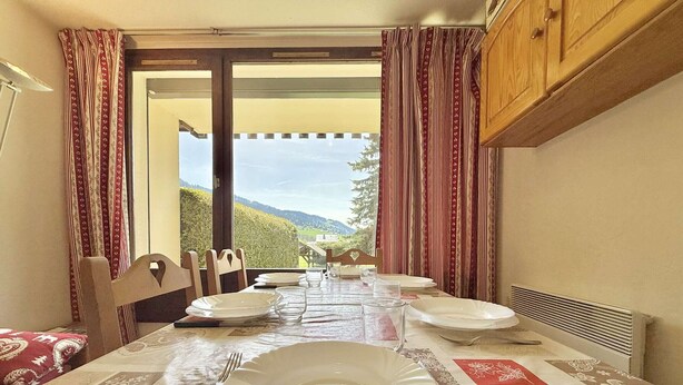 A dining table set for four with a view of the outdoors.