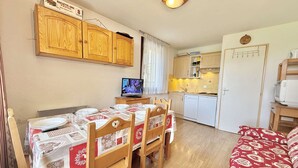 A compact living space with a dining area, kitchenette, and a cozy sitting area.