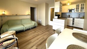 Un espace de vie compact comprenant un canapé, une table à manger et une kitchenette.