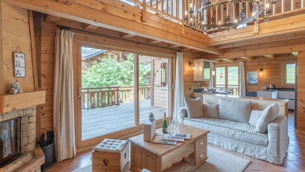 A spacious wooden cabin with a cozy living area, a fireplace, and a balcony overlooking a forested area. - 178m2 Chalet in Alpe d'Huez Ski-in/Ski-out with Terrace (Huez)