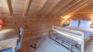 A wooden cabin bedroom with a bed, a desk, and a chair. - 178m2 Chalet in Alpe d'Huez Ski-in/Ski-out with Terrace (Huez)