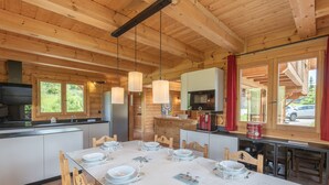 A wooden cabin with a dining area set for four, equipped with a refrigerator, microwave, and a coffee machine. - 178m2 Chalet in Alpe d'Huez Ski-in/Ski-out with Terrace (Huez)