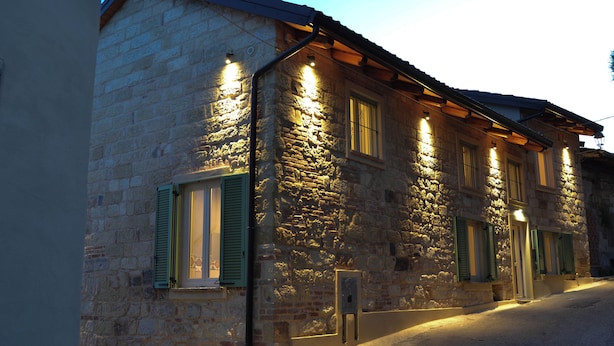 Un edifici de pedra amb persianes verdes i diverses finestres il·luminades, que reflecteix un estil arquitectònic tradicional.