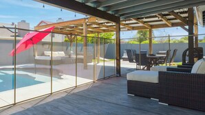 Ein überdachter Außenbereich mit Pool, Sitzgelegenheiten und einer Pergola.