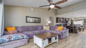Ein Wohnzimmer mit Ecksofa, Couchtisch und Deckenventilator.