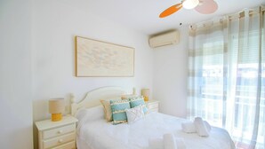 A neatly arranged bedroom with a bed, bedside tables, a lamp, and a ceiling fan. - Penthouse Kalymnos (Platja de L'arenal)