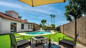 Un jardin avec une piscine, un foyer extérieur et des meubles de jardin.