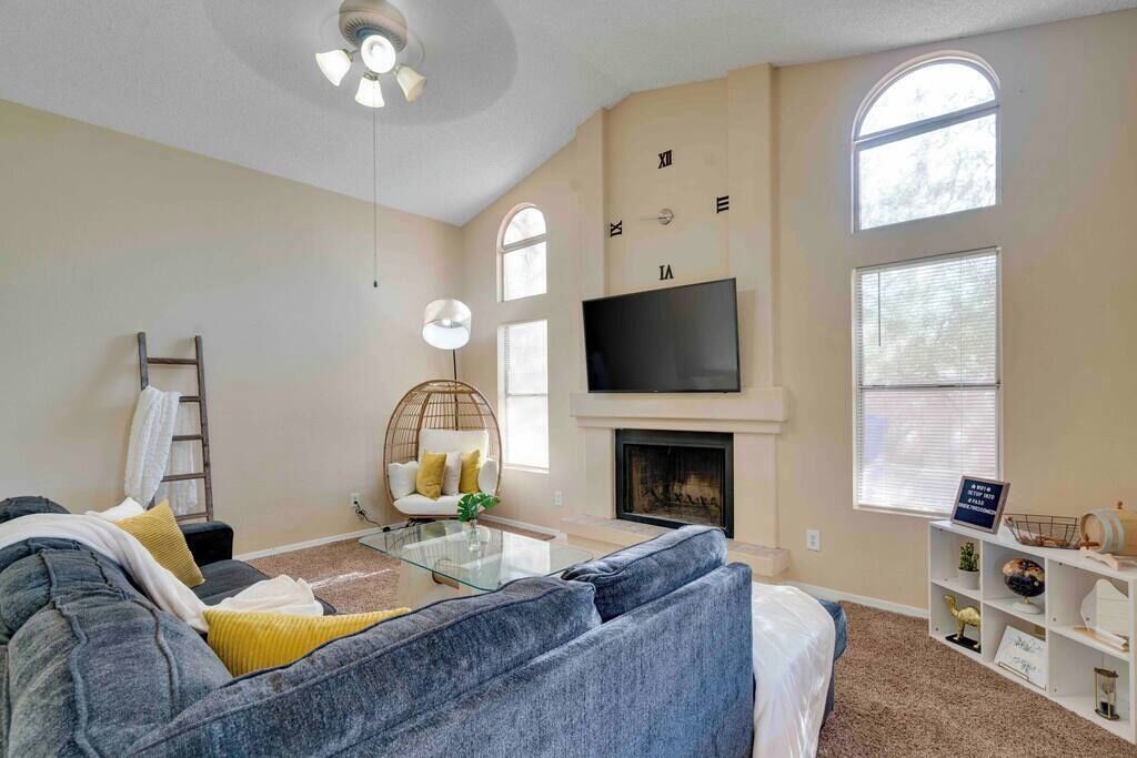 A living room with a fireplace, a television mounted above it, and a large window.