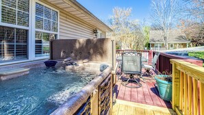 A hot tub on a wooden deck with a stone wall, a television, and a potted plant. - Convenient to Dollywood-Dinner Shows Two Bedroom Two Bathroom- Internet Access (Pigeon Forge)