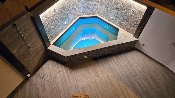 A hexagonal hot tub with a stone exterior and a wooden floor surrounding it. - NEXT HOUSE, FURNAS, Vila center (Furnas)