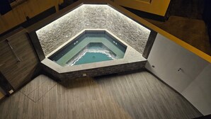 A hexagonal hot tub with a stone exterior, surrounded by wooden flooring and a wooden bench. - NEXT HOUSE, FURNAS, Vila center (Furnas)