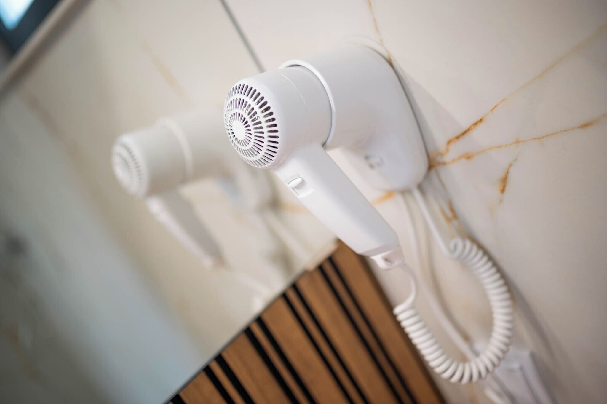 Ein an der Wand befestigter Haartrockner mit aufgewickeltem Kabel.
