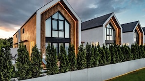 A modern residential building with large windows and a wooden facade. - Olivina Park domy w kompleksie Spa  (Rewal)