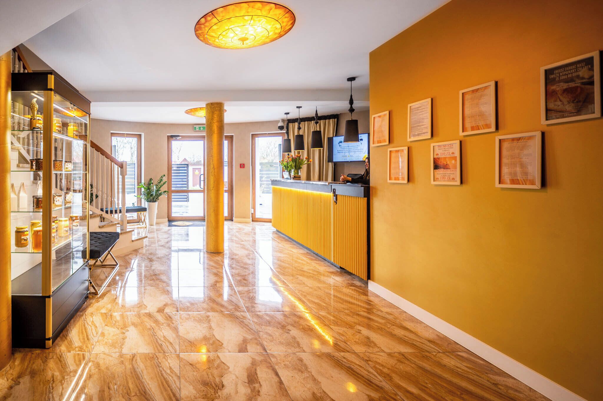A hotel lobby with a marble floor, a reception desk, and framed certificates on the wall.
