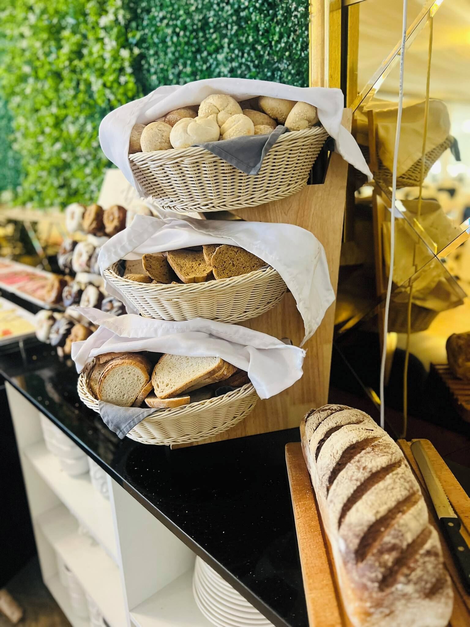 Erilaisia leipiä ja leivonnaisia on esillä koristekoreissa, ja oikealla puolella on leikkuulaudalla yksi leipä.