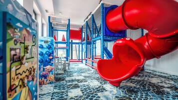 Ein Kinderspielbereich mit Rutsche, Spielgeräten und einer Wandmalerei.