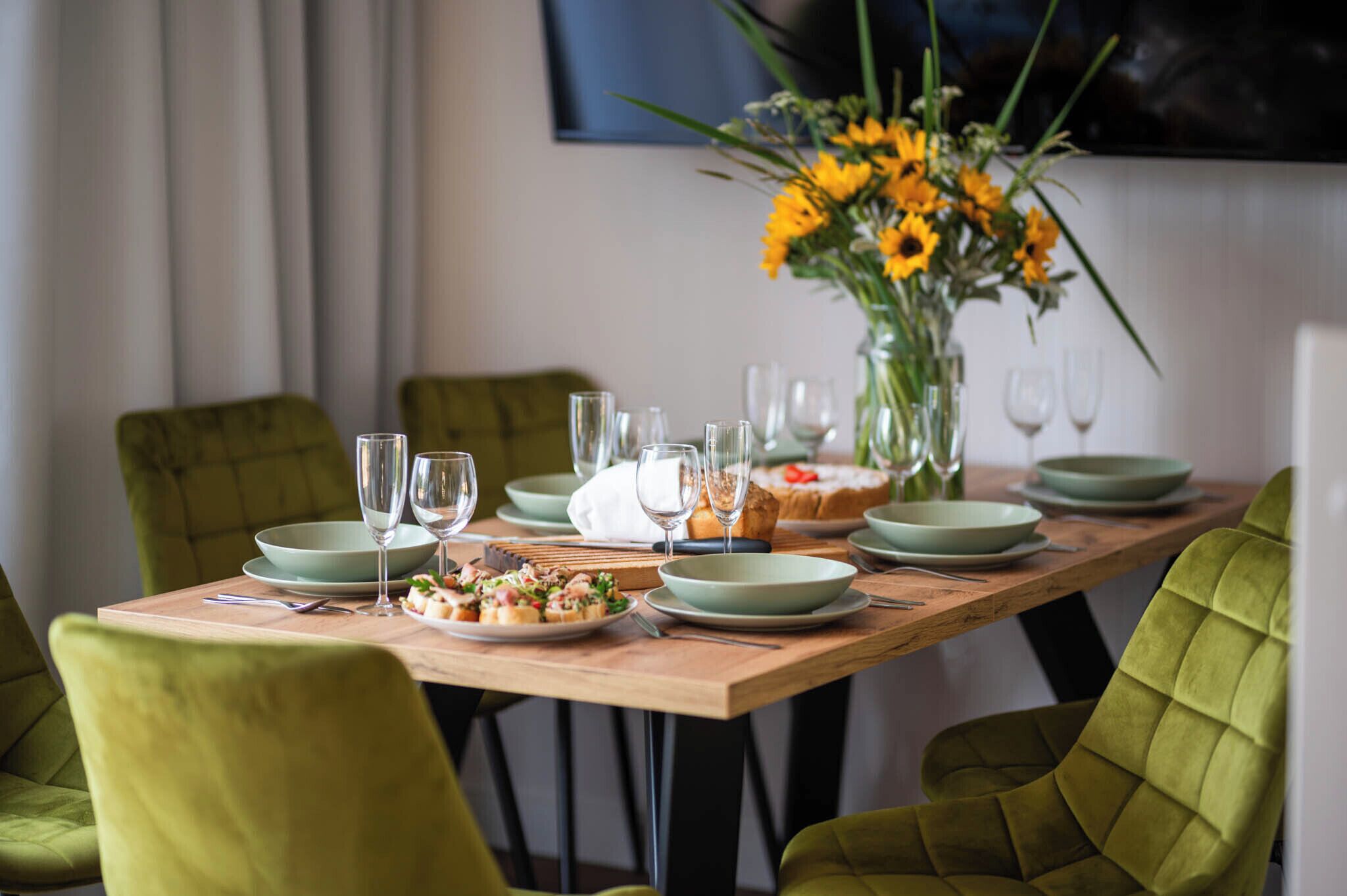 Una mesa de comedor dispuesta con platos, vasos y un florero.