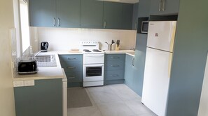 A compact kitchen with a stove, oven, microwave, and a toaster.