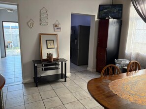 Ein Essbereich mit Tisch, Stühlen, einem Fernseher und einem Kühlschrank.