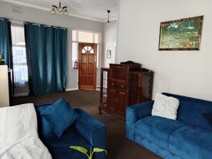 Ein Wohnzimmer mit einem blauen Sofa, einem weißen Sofa, einer Holzkommode und einem Bild an der Wand.