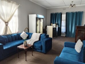 Ein Wohnzimmer mit blauem Sofagarnitur, einem Couchtisch und einem Kühlschrank.