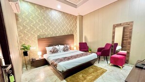 A bedroom with a large bed, two nightstands, a desk, a chair, and a mirror. - Hotel Pearl Grand by Elena Group (Dera Bassi)