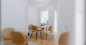 A modern, minimalistic dining area with a wooden table and chairs, a window with a view, and a clean, white interior. - 2BD Flat Perfect for Remote Workers, ExCel London (Greater London)