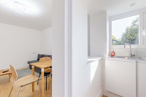 Une cuisine moderne avec une fenêtre, un coin repas comprenant une table et des chaises, et un canapé gris.