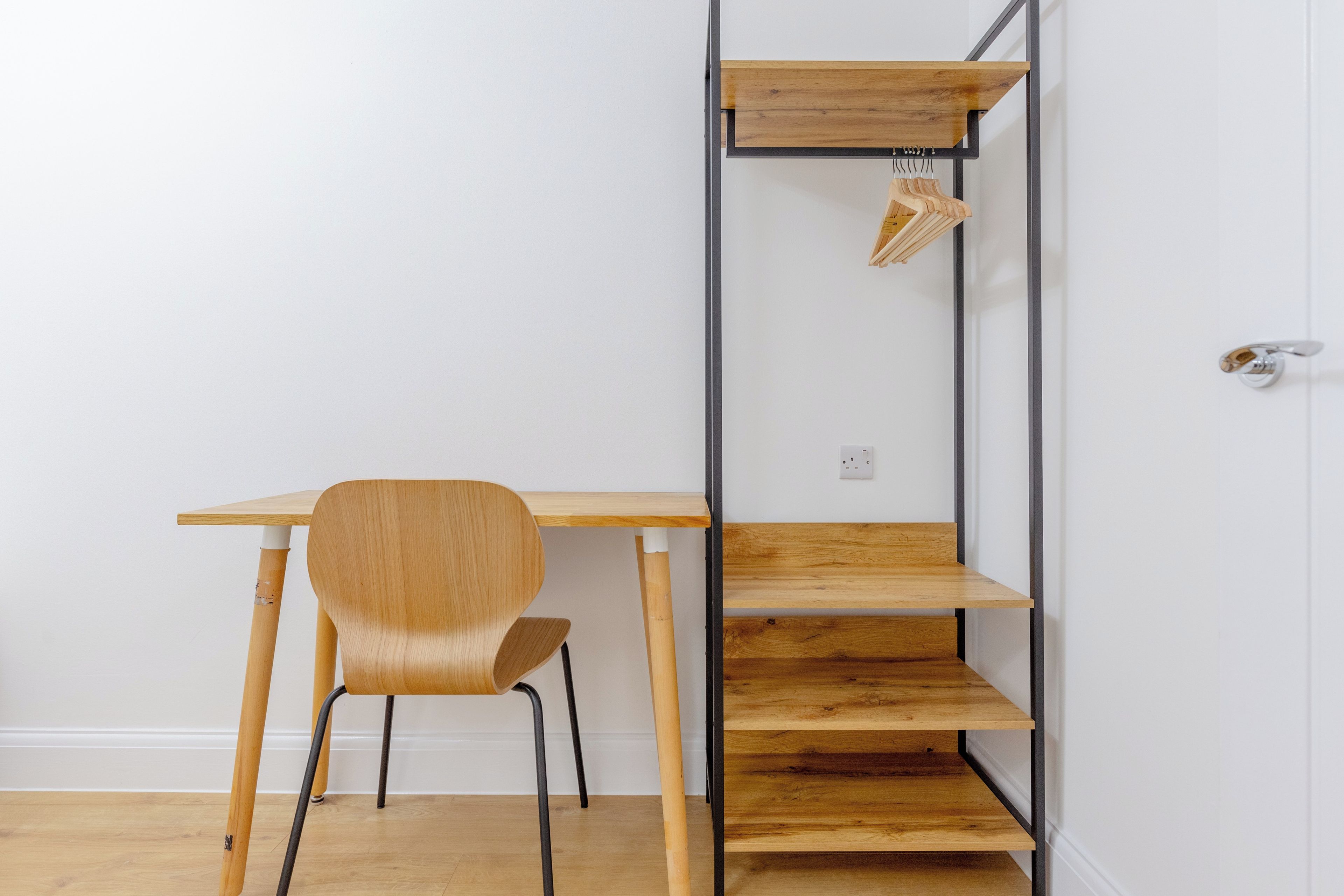 A minimalist room with a wooden desk, a chair, and a built-in shelving unit.