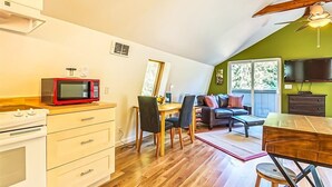 A compact kitchen with a microwave, stove, and wooden dining table. - Studio Loft in the Woods|Washer & Dryer|Workspace (Sequim)
