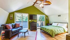 A bedroom with a sloped ceiling, a bed, a sofa, a TV, and a dresser. - Studio Loft in the Woods|Washer & Dryer|Workspace (Sequim)