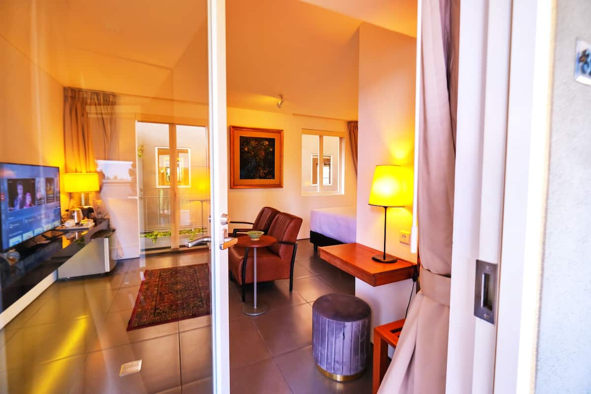 A hotel room with a bed, a desk, a chair, a TV, and a lamp.