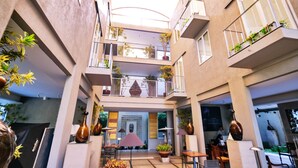 A multi-level atrium with balconies, potted plants, and seating areas. - KoenoKoeni Boutique Hotel (Parongpong)