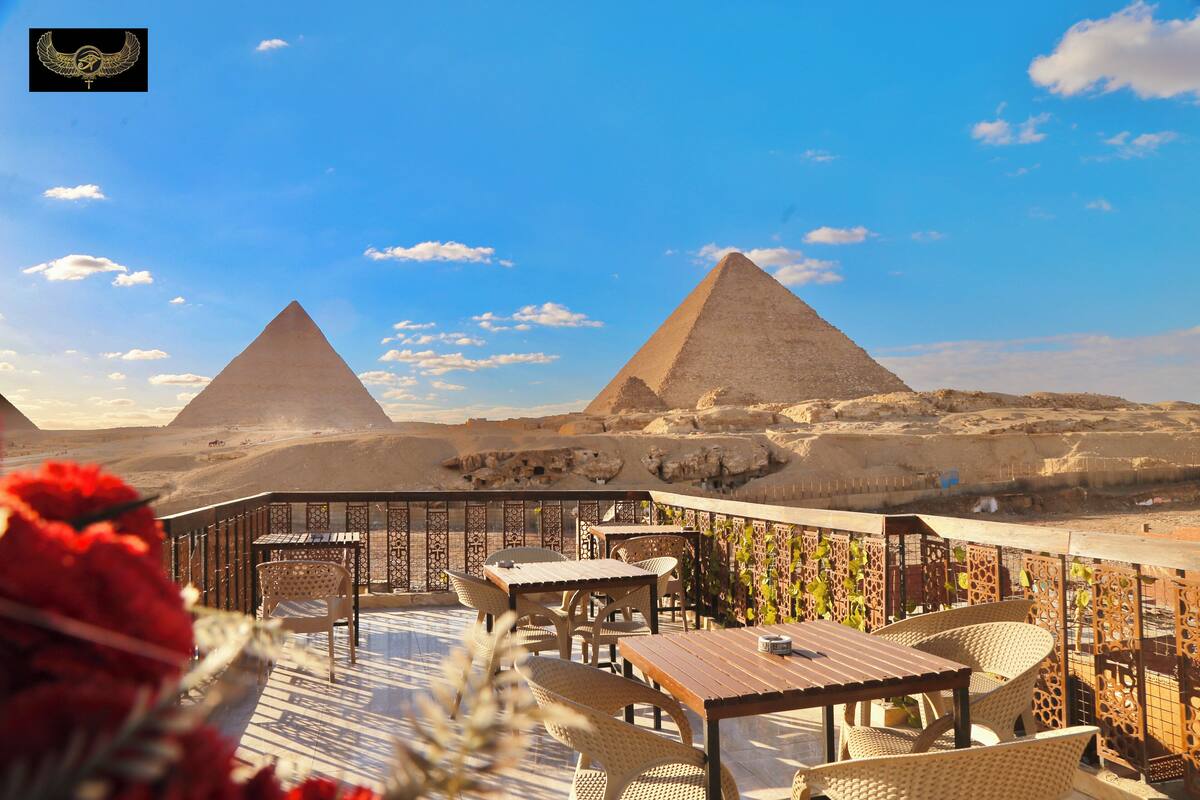 A terrace with wicker furniture and a view of the pyramids.