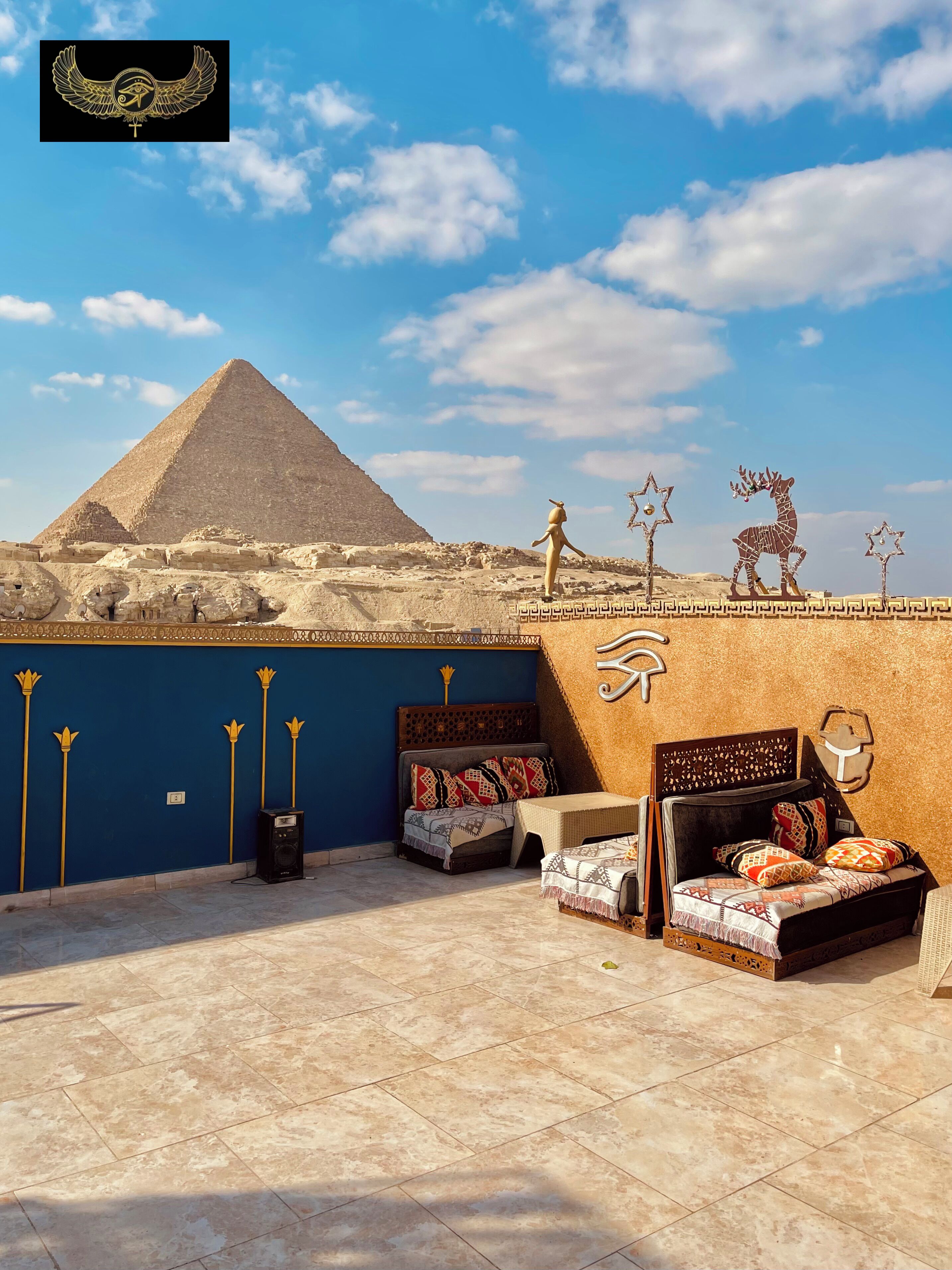 A room with a view of the pyramid, a bed, a small table, and decorative wall art.