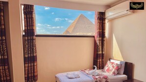 Camera d'albergo con due letti, una scrivania e vista sulla piramide.