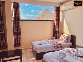 A hotel room with two beds, a desk, and a view of the pyramid.