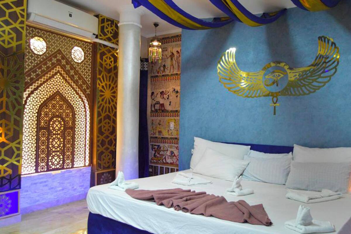 A hotel room with a large bed, decorative wall art, and intricate architectural details.