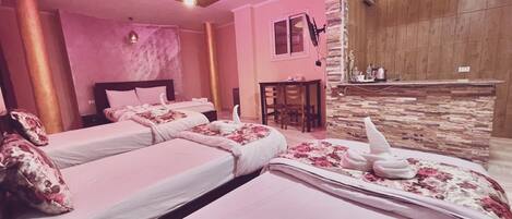 A hotel room with two beds, a stone accent wall, a small desk, and a reception area.